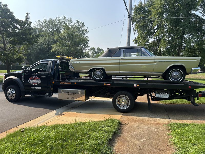 RR Towing & Recovery black Jerr-Dan flatbed hauling a classic Mercury convertible in Grand Haven, Michigan